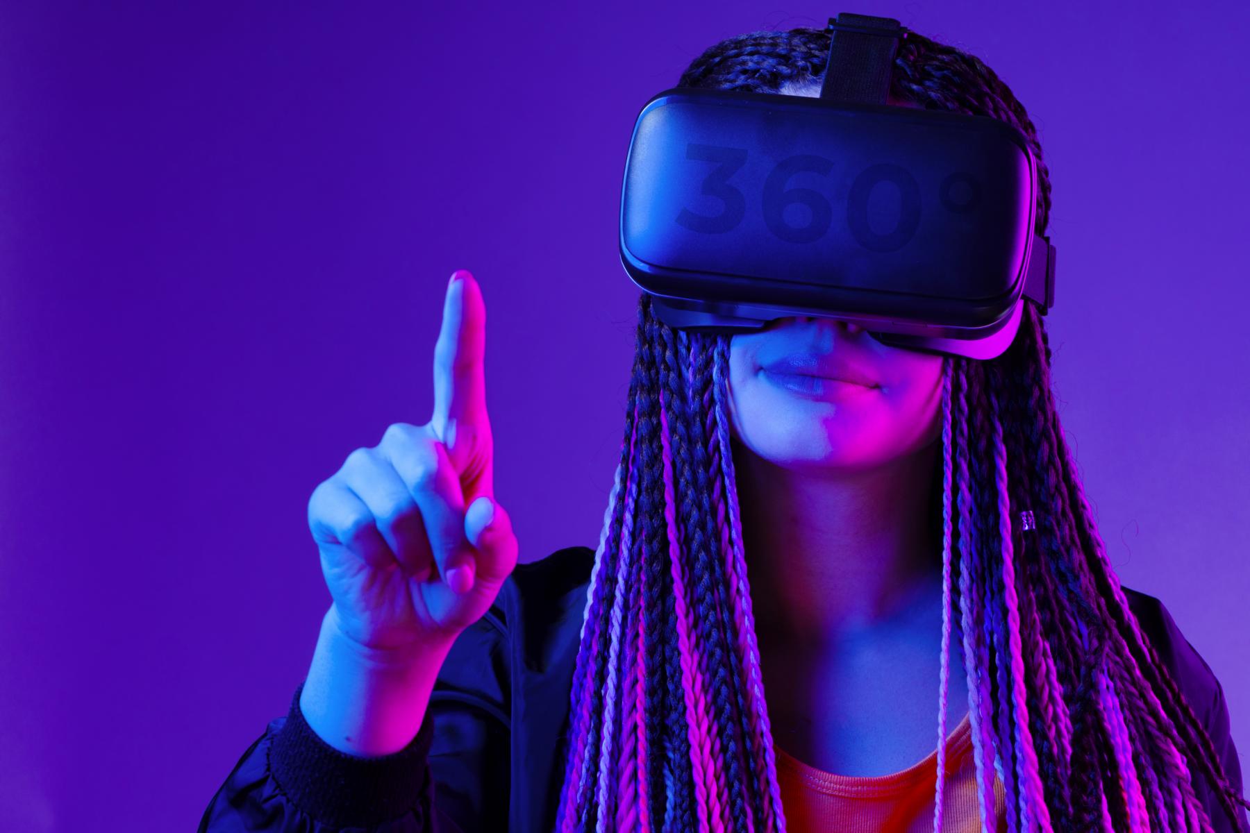 Young woman with afro braids using VR glasses on dark purple neon background close up. The VR is a great Usability prototyping tool.